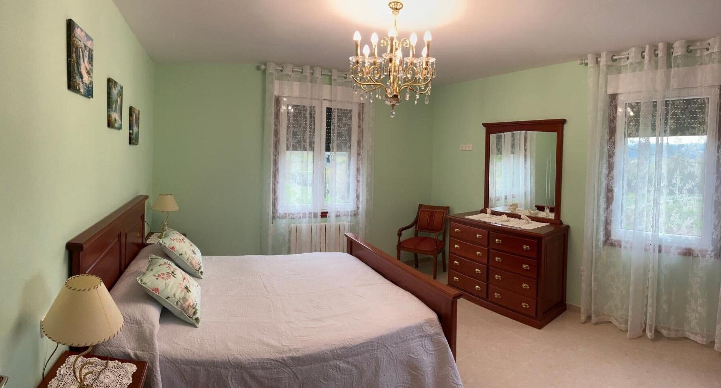 Une chambre à coucher avec un lit, une commode, une chaise et un lustre.