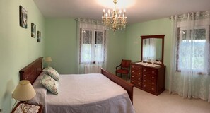 Un dormitorio con cama, cómoda, silla y candelabro.
