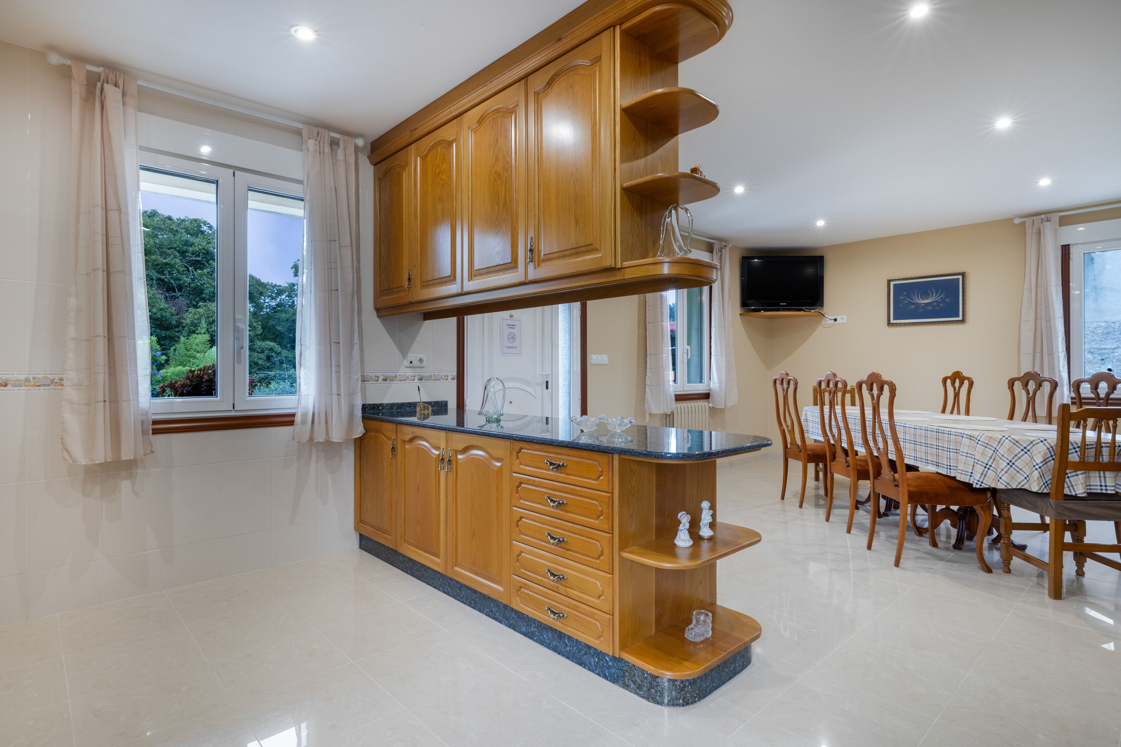 Una cucina con mobili in legno, un piano di lavoro in granito e un'area pranzo con sedie e tavolo in legno.