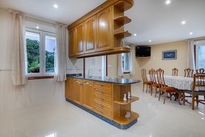 A kitchen with wooden cabinets, a granite countertop, and a dining area with wooden chairs and a table.