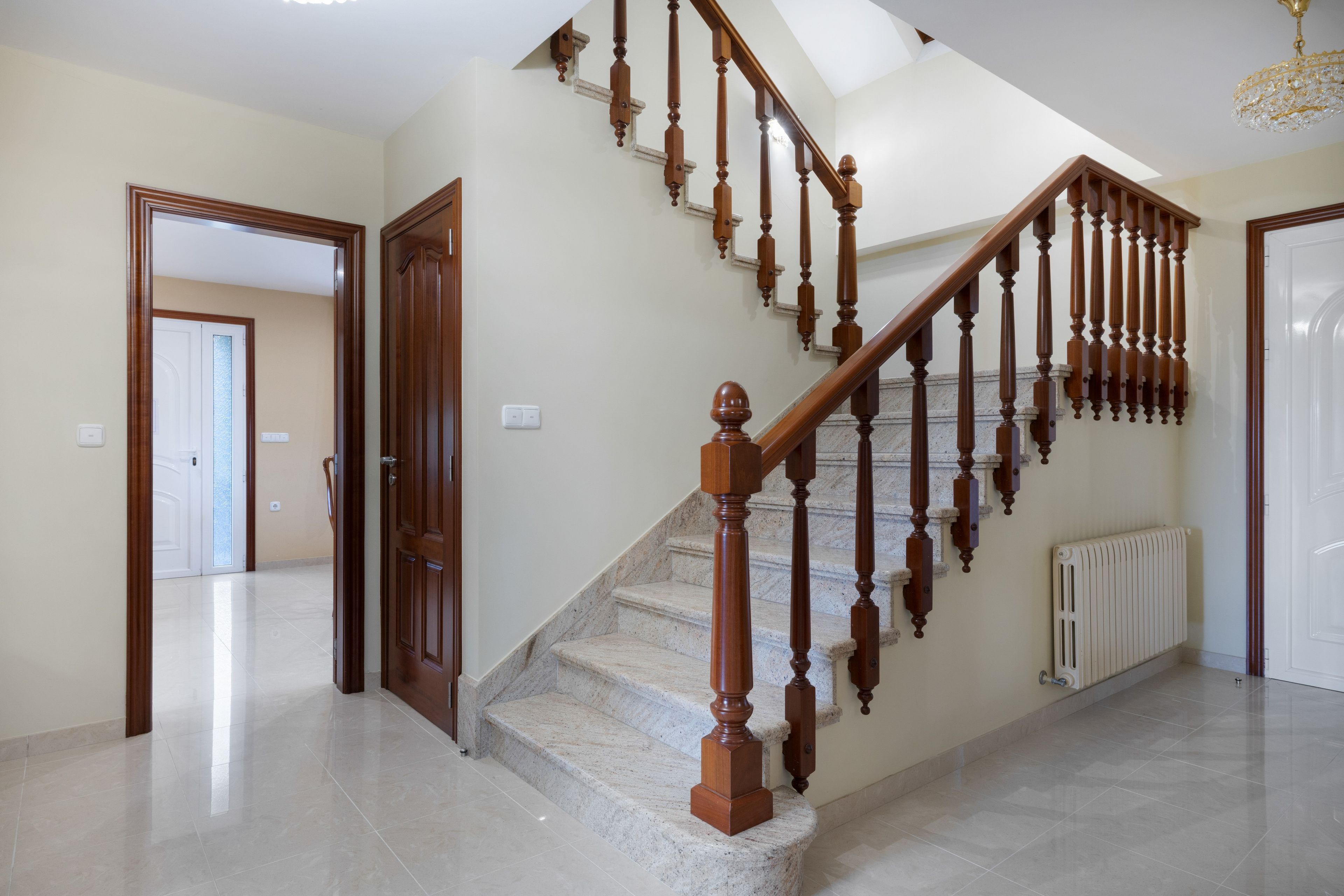 A staircase with wooden balusters and a marble floor leading to an upper level.