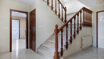 A staircase with wooden balusters and a marble floor leading to an upper level.