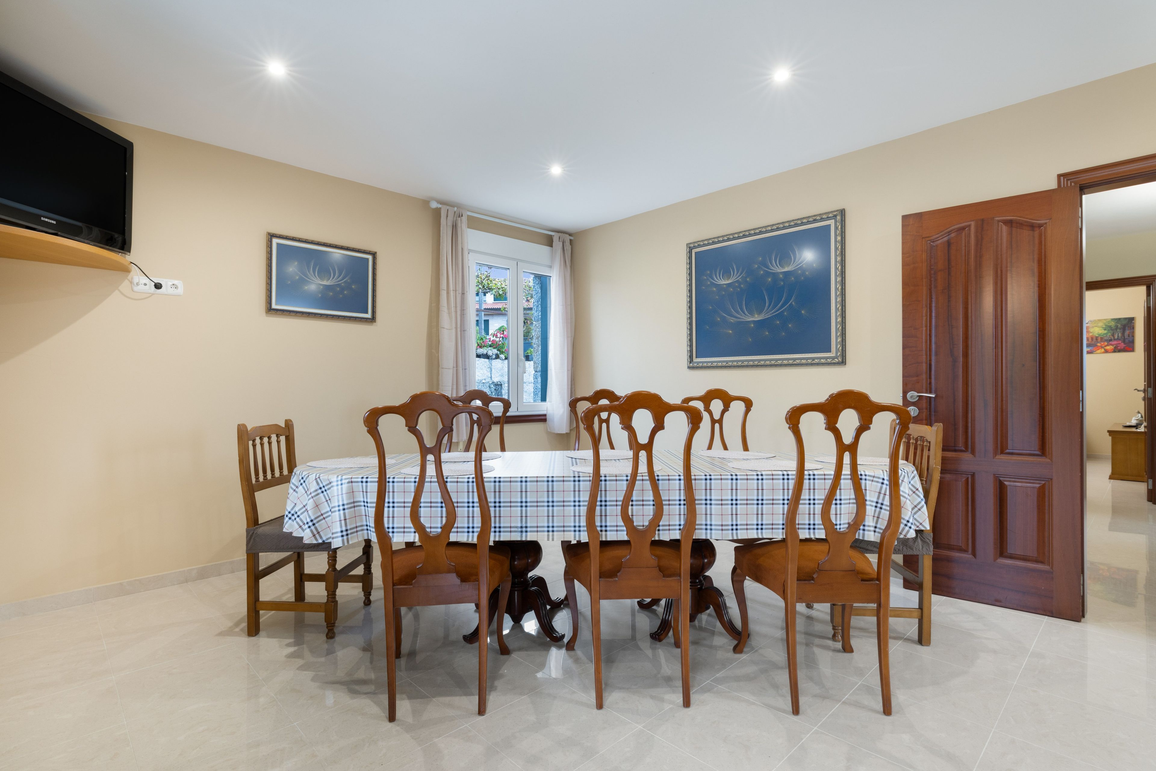 A dining area with a table set for six, surrounded by wooden chairs with curved backs.