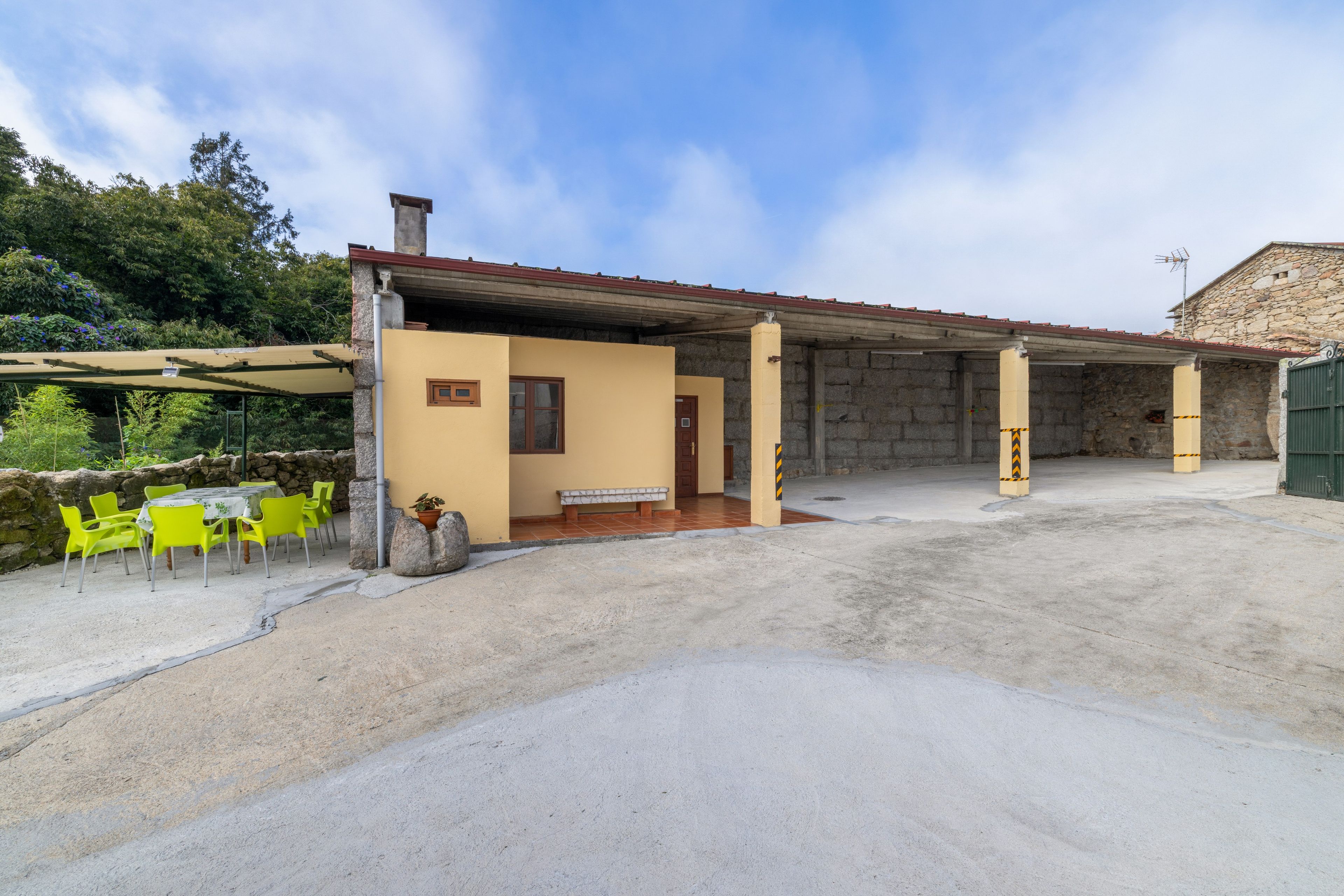 Un edificio con un patio techado, paredes de piedra y una puerta verde.