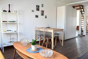 A dining area with a wooden table, clear chairs, and a white cabinet with shelves. - Rooftop terrace loft apartment, home cinema (Praha 10)