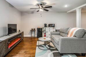 Un salon avec une cheminée, un canapé, une table basse et un ventilateur de plafond.