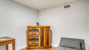 A corner room with a wooden cabinet, a grey sofa, and a small table.