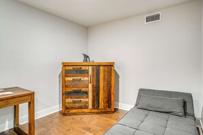 A corner room with a wooden cabinet, a grey sofa, and a small table.