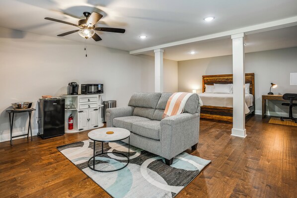 A modern living room with a grey sofa, a coffee table, and a ceiling fan. - Hilltop Studio Hideaway Near Chattanooga (Middle Valley)