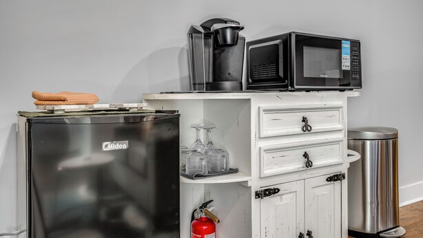A kitchenette with a refrigerator, microwave, coffee maker, and a small cabinet with drawers.