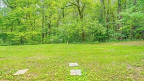 A grassy area with a stone pathway leading through a wooded area.
