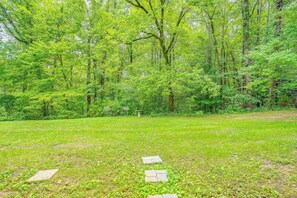 A grassy area with a stone pathway leading through a wooded area.