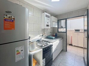 A modern kitchen with white cabinets, a built-in oven, a gas stove, and a microwave. A refrigerator with a Gafa energy label is visible. - Beautiful 2 bedrooms in the Heart of Palermo (Buenos Aires)