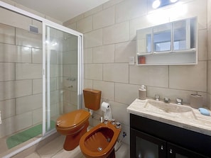 Un baño con inodoro, bidé y cabina de ducha.