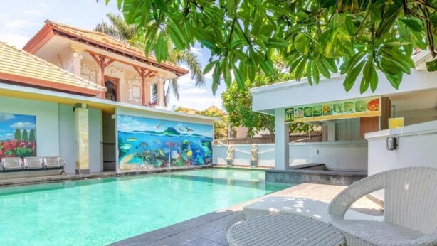 Ein Swimmingpool mit Wandmalerei, Korbmöbeln und einer Bar.