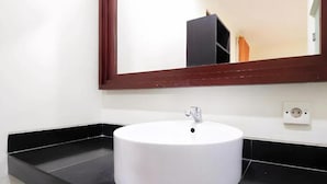 Ein Badezimmer mit einem weißen Waschbecken, einer schwarzen Arbeitsplatte und einem Spiegel mit Holzrahmen.