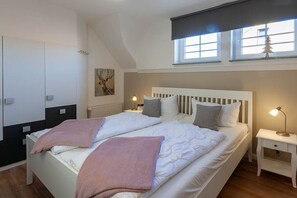 Une chambre avec un grand lit, deux tables de chevet, une armoire et une fenêtre donnant sur un beau paysage.