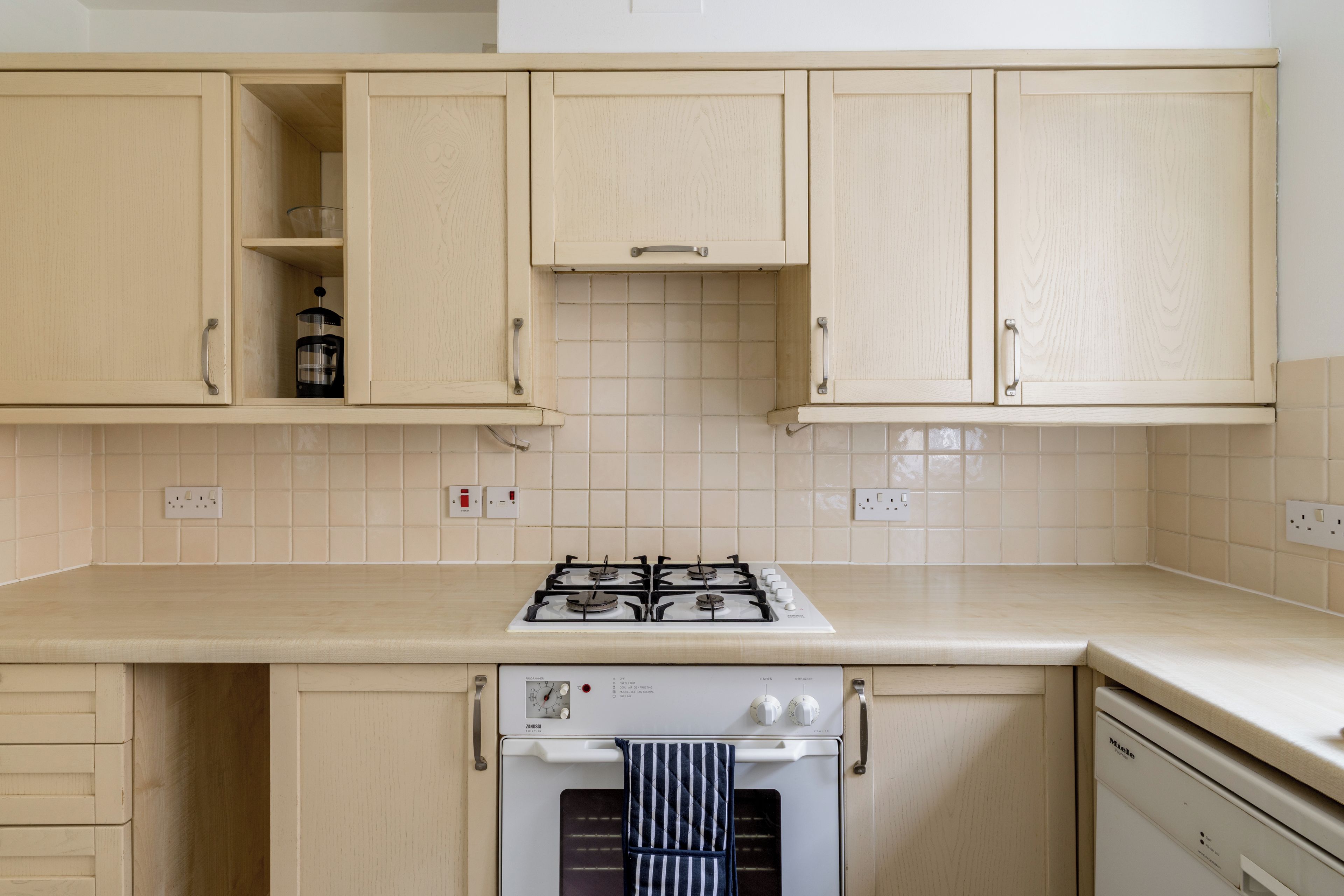 A kitchen with a gas stove, oven, and a coffee maker on the counter.