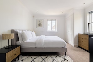 A bedroom with a bed, bedside tables, a lamp, a framed picture, and a window. - Green Light in Brondesbury Park (London)