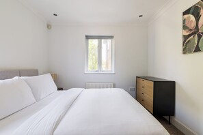 A bedroom with a bed, a radiator, a window, and a dresser. - Green Light in Brondesbury Park (London)