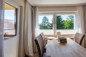 A room with a dining table, two chairs, and a window with curtains. - Holiday apartment with 2 bedrooms (Braunlage)