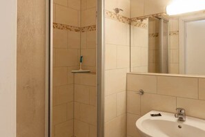 A bathroom with a shower, a sink, and a mirror. - Holiday apartment with 2 bedrooms (Braunlage)