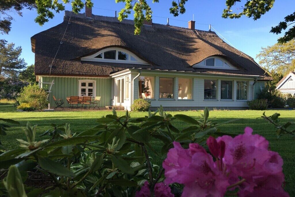 A house with a thatched roof, a porch, and a well-maintained lawn.