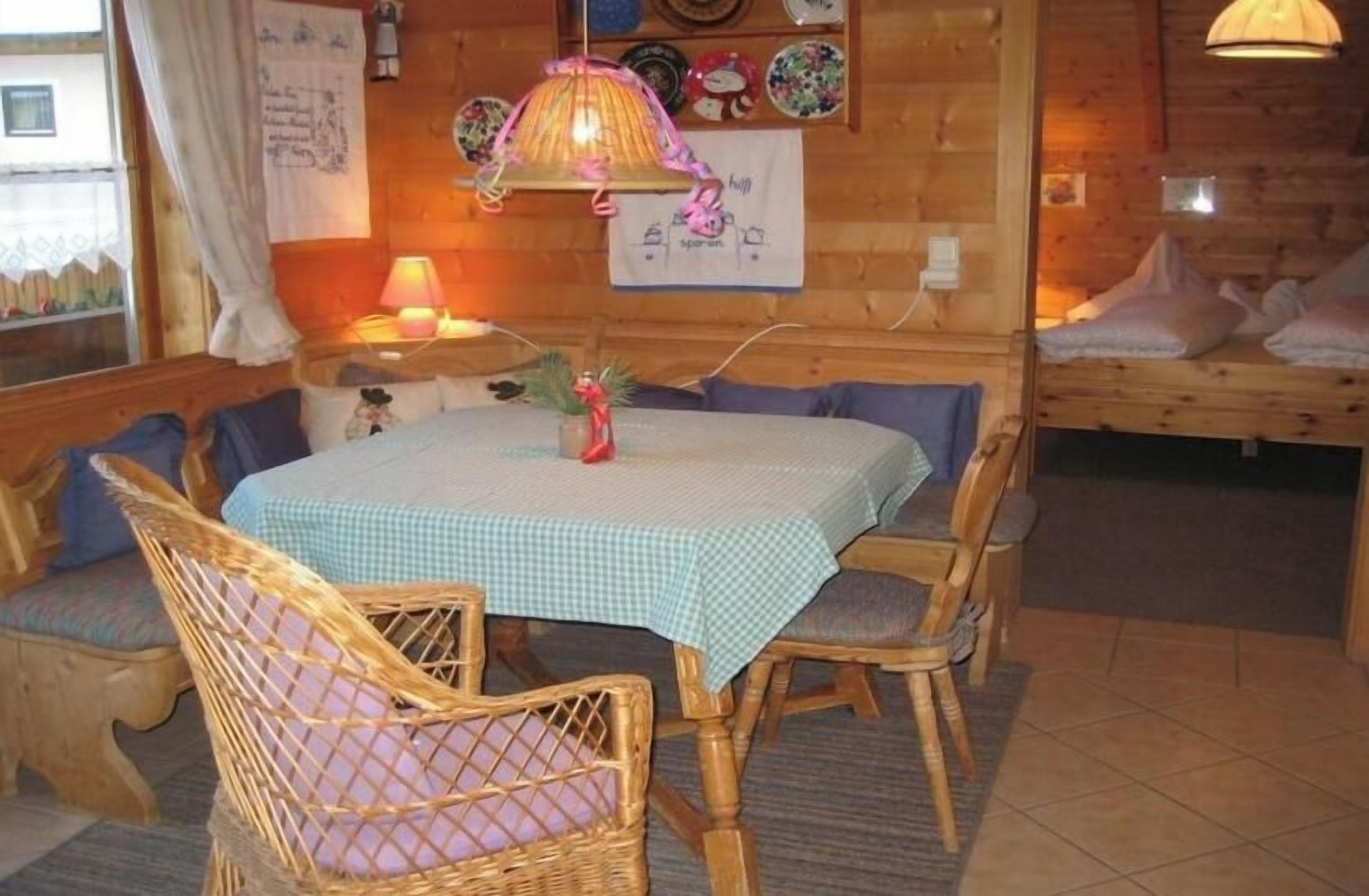 Un coin repas avec une table dressée pour quatre personnes, entourée de chaises en osier.