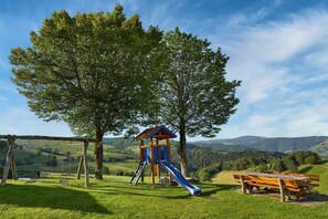 A playground with a slide and swings, a picnic table, and a scenic view of hills and trees. - Holiday apartment with 2 bedrooms (Münstertal)