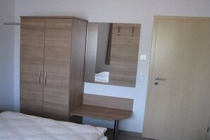 A bedroom with a bed, a wardrobe, a mirror, and a door. - Carp House - Courtyard Pond (Feuchtwangen)