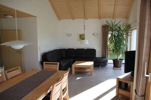 A living room with a black sofa, wooden coffee table, and a TV stand. - Carp House - Courtyard Pond (Feuchtwangen)