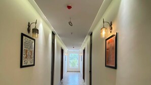 Un pasillo con piso estampado, luminarias fijadas a la pared y cuadros enmarcados.