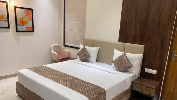 Un dormitorio moderno con una cama grande, una mesita de noche, una silla y dos cuadros en la pared.