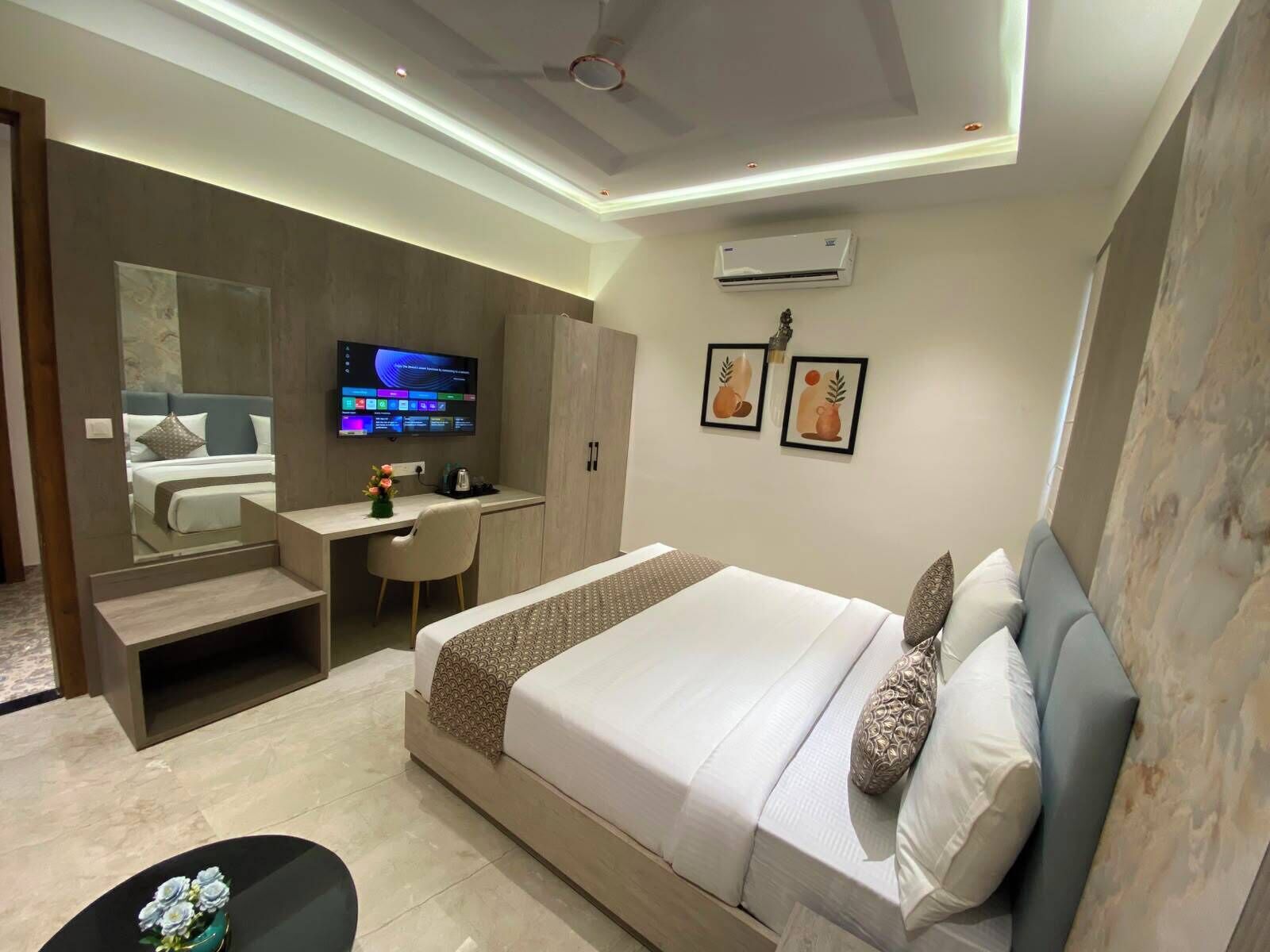 Una habitación de hotel moderna con una cama grande, un escritorio, una silla, un televisor y obras de arte en las paredes.
