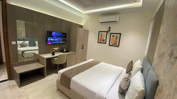 Una habitación de hotel moderna con una cama grande, un escritorio, una silla, un televisor y obras de arte en las paredes.
