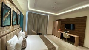 Ein modernes Hotelzimmer mit einem großen Bett, einem Schreibtisch, einem Fernseher und Blick auf die Stadt.
