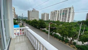 Un balcón con vistas a una carretera, edificios y vegetación.