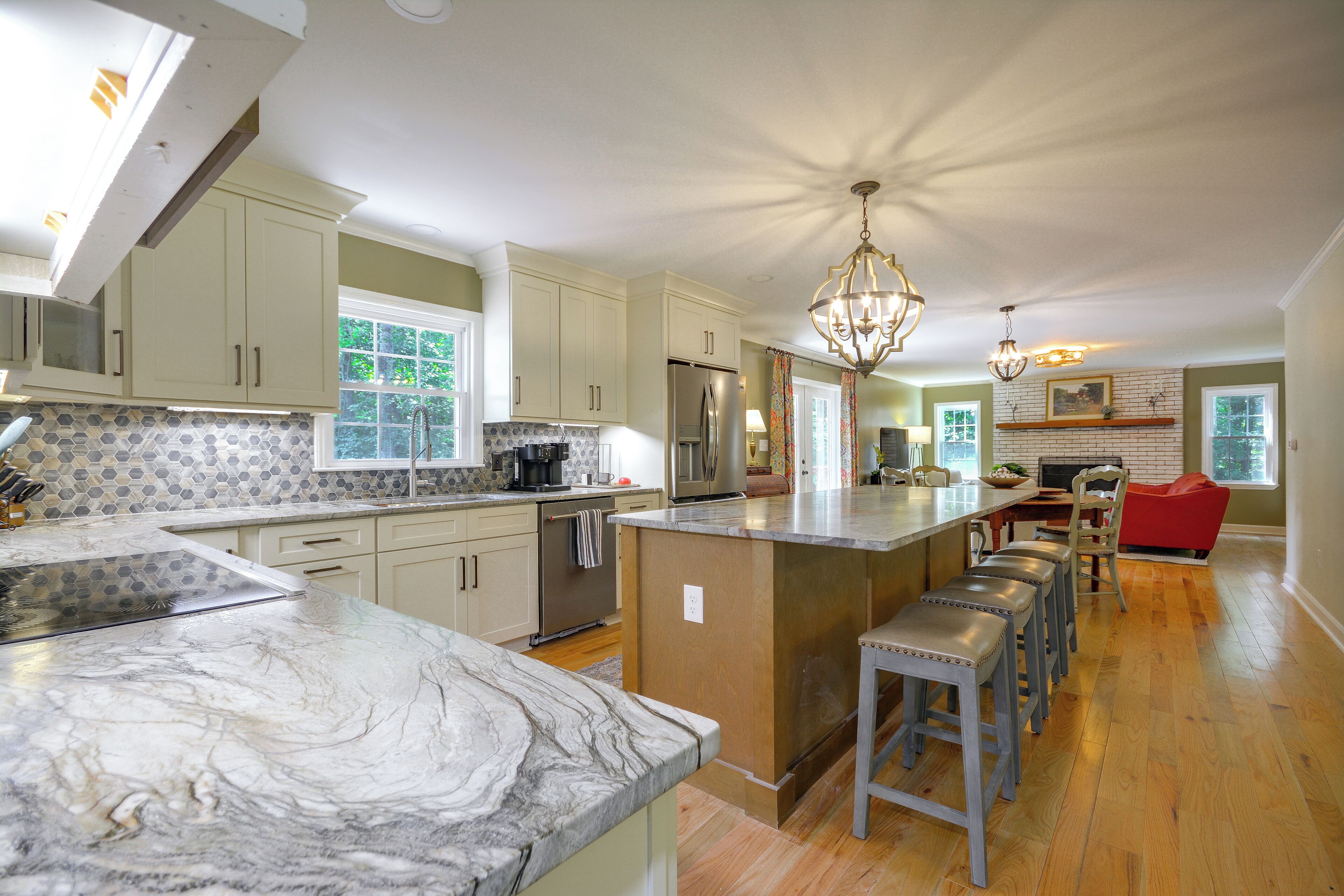 A spacious kitchen with a marble countertop, stainless steel appliances, and a central island with bar stools.