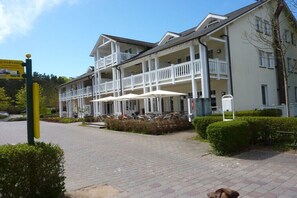 A hotel with a covered outdoor seating area, multiple balconies, and a paved entrance. - Holiday apartment with 1 bedroom (Ostseebad Binz)
