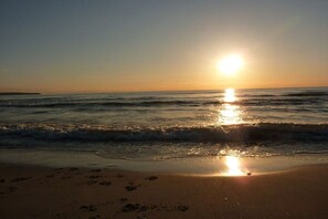 A beach with the sun setting over the water, creating a reflection on the sand. - Holiday apartment with 1 bedroom (Ostseebad Binz)
