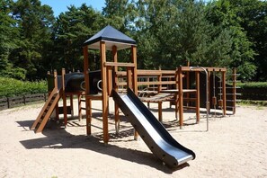 A playground with a slide, climbing structures, and a covered play area. - Holiday apartment with 1 bedroom (Ostseebad Binz)