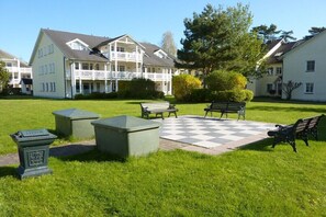 A courtyard with a checkered pavement, benches, and a building with balconies. - Holiday apartment with 1 bedroom (Ostseebad Binz)