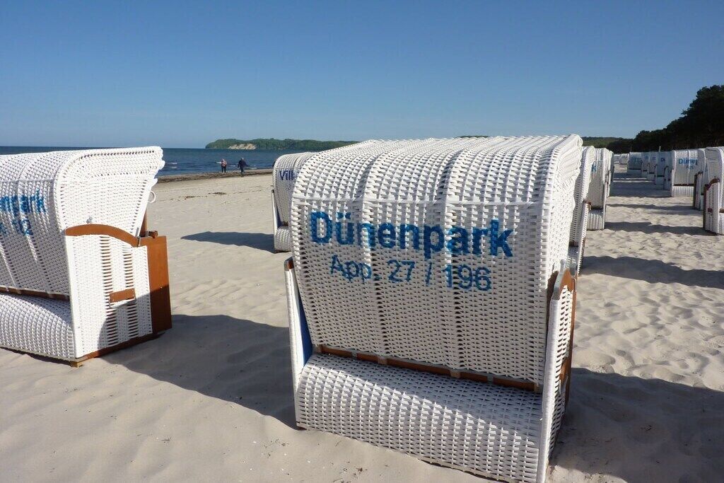 Beach chairs with 'Dunenpark' text and a date on them, arranged on a sandy beach.