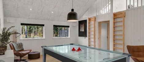 A modern room with a foosball table, a comfortable seating area, and large windows providing natural light.