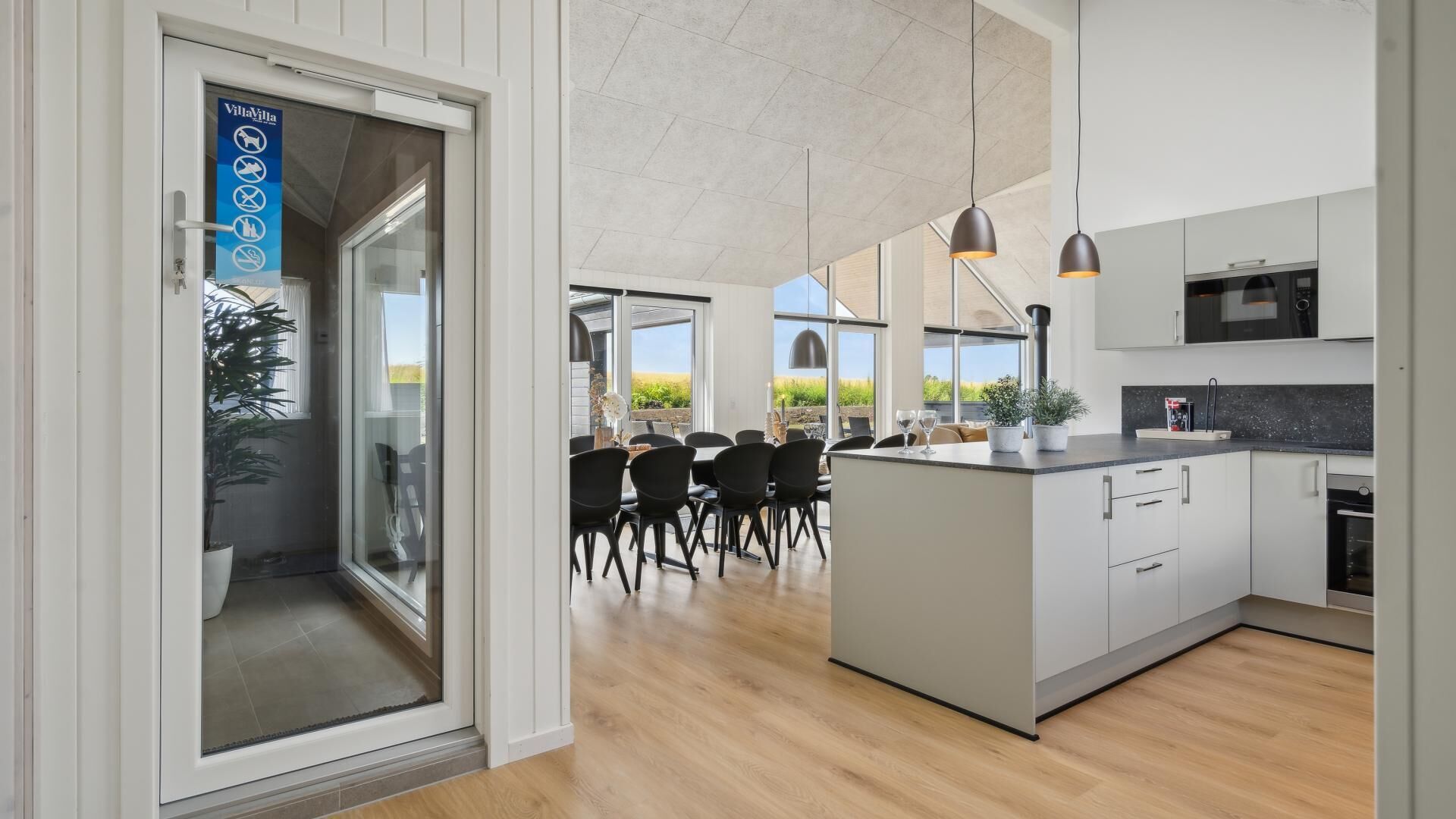 A modern kitchen with a central island, pendant lighting, and a view of the outdoors.
