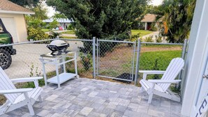 Un'area patio con due poltrone Adirondack, un barbecue e un tavolo in metallo.