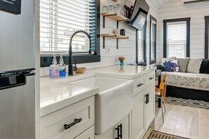 Eine kleine Küchenzeile mit Spüle, Stauschranken und einem Fenster mit Jalousien.
