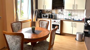 Cocina compacta con comedor, que incluye una mesa redonda, sillas, microondas, horno y armarios.