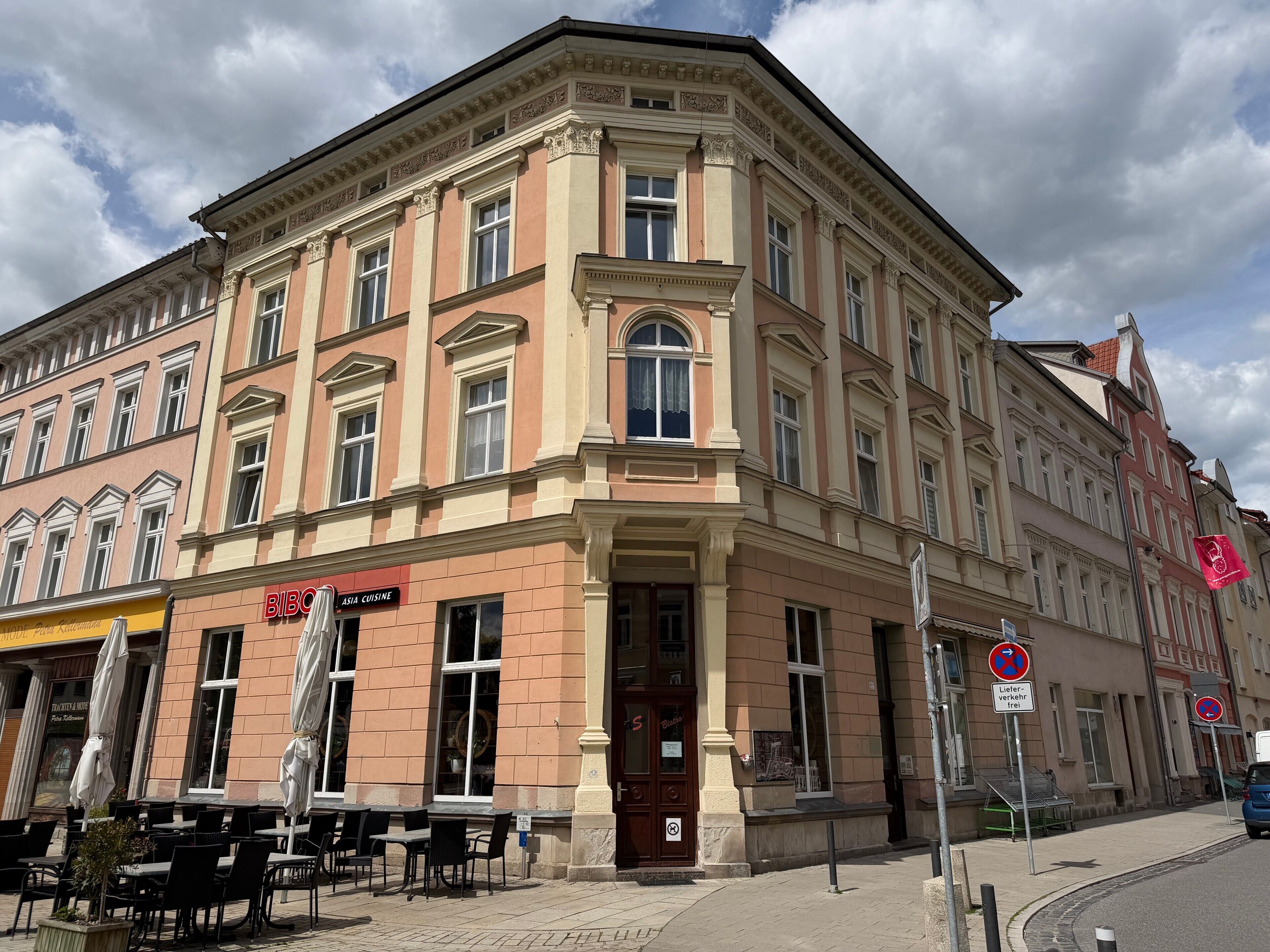 Ein Eckgebäude im traditionellen Stil, mit einem Laden im Erdgeschoss, der mit einem Schild für 'Asia Cuisine' versehen ist.