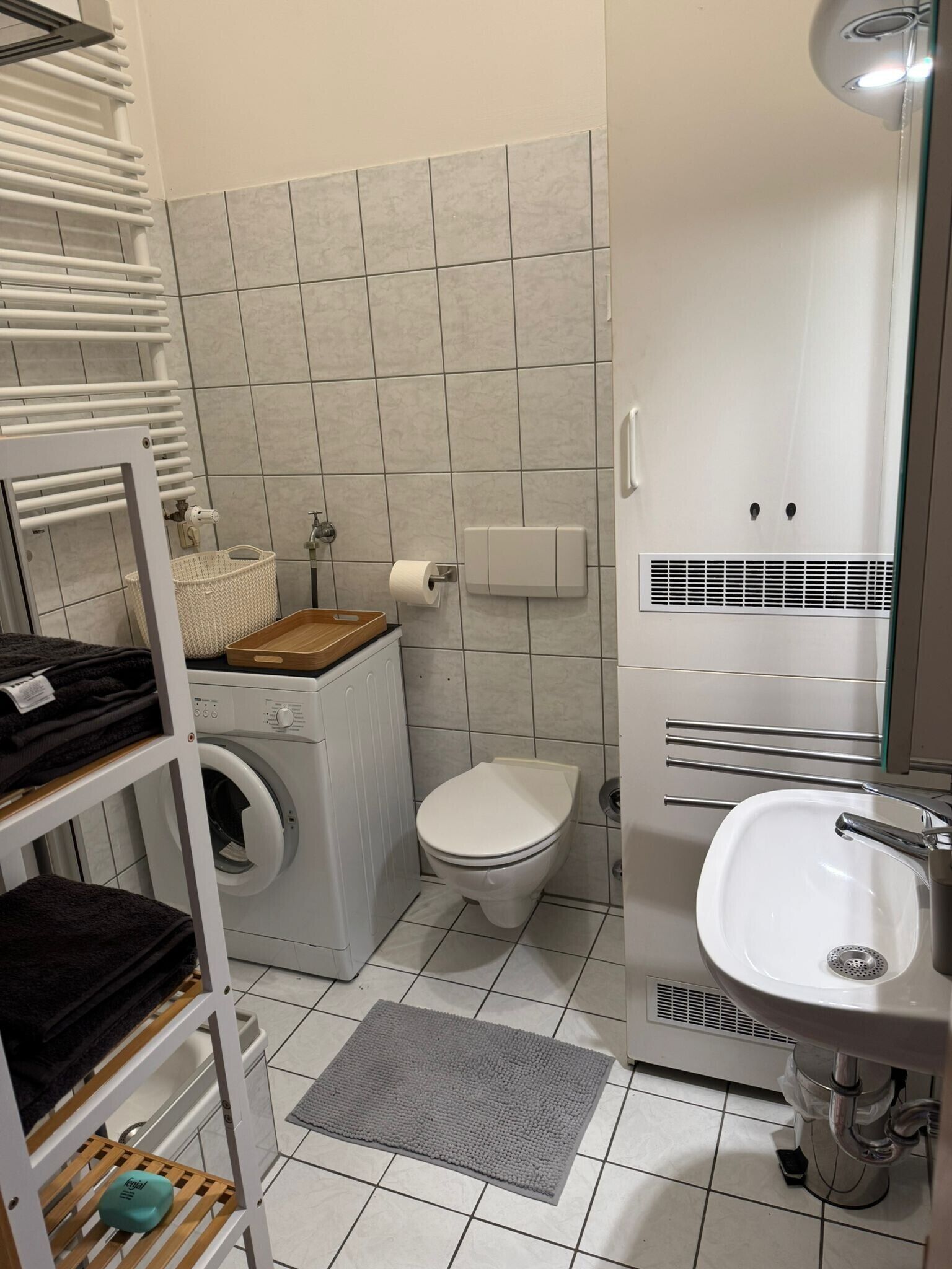Ein kleines Badezimmer mit Waschmaschine, Toilette und Waschbecken.
